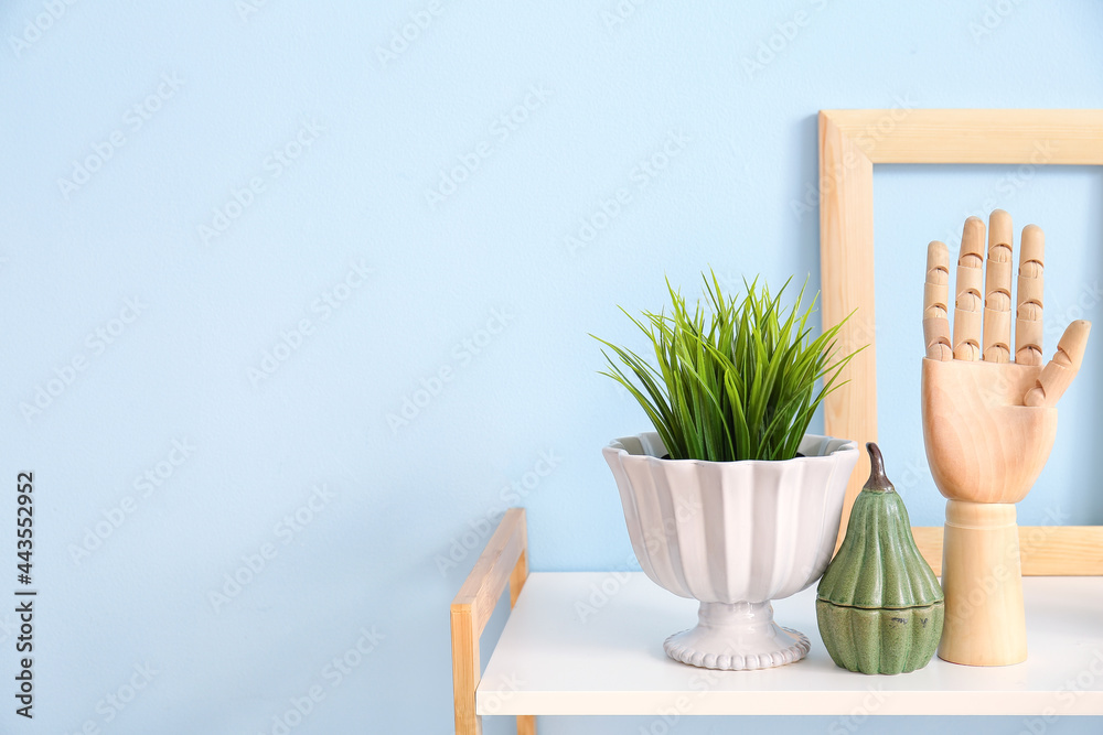 Wooden hand and decor on shelf near color wall