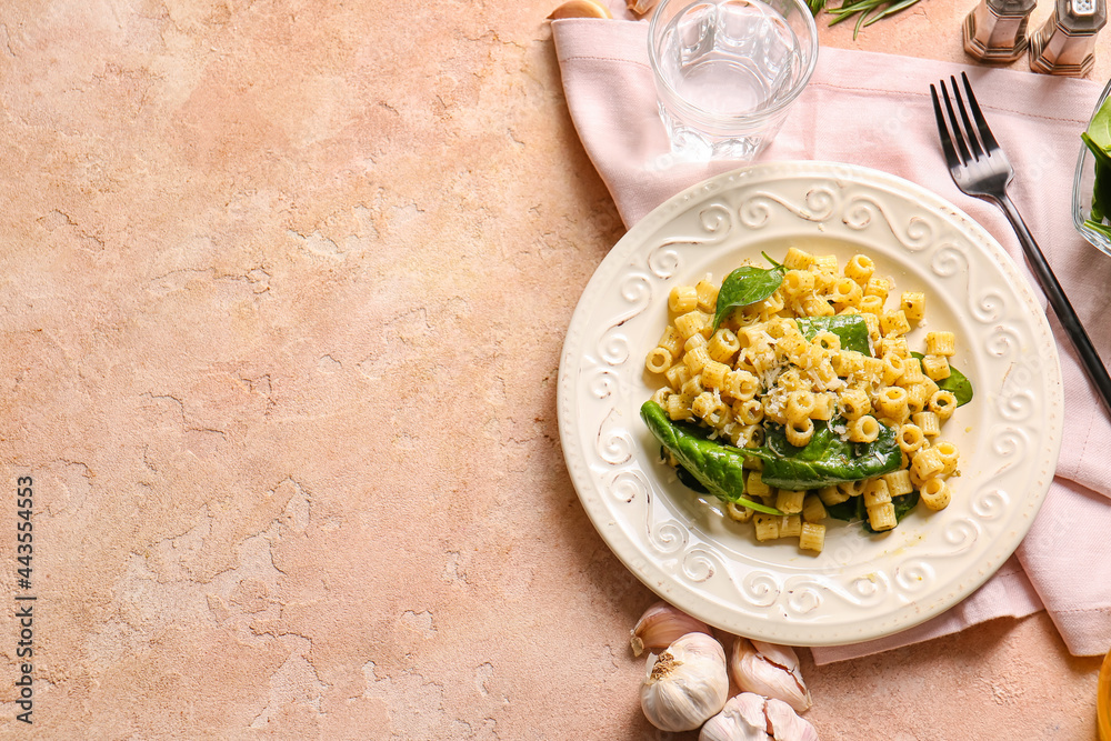Plate with tasty pasta and spinach on color background