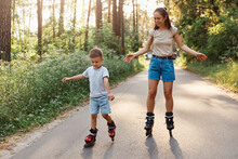 Portrait Of Smiling Mother And Son Learn To Roller Skate, Mom With Child Having Fun On Roller Skates In Summer Park Together, Concentrated Kid Rollerblading, Mommy Rejoices His Success.