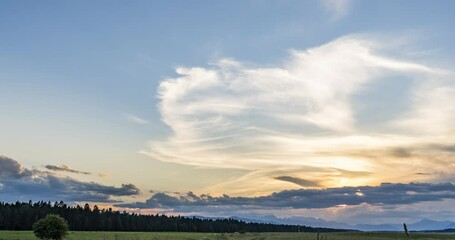 Wall Mural - Time lapse of beautiful and colorful sunset over farming field. Grassland in the foreground. Alps in the distance. Pristine farmland in Slovenia. Right tracking, wide angle