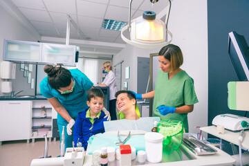 Wall Mural - Professional dentist team and two young boys as patients at the dental office