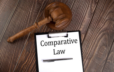Poster - COMPARATIVE LAW text on paper with gavel on wooden background