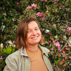 Happy adult woman on background of blooming spring tree in park