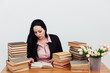 © dmitriisimakov - beautiful business woman in business suit at a table with stacks of educational books
