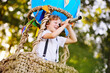 © Evgeniy Kalinovskiy - a small boy with curly hair with a spyglass in his hands against the background of a blue balloon basket smiles and looks into the distance.