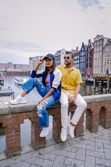 Wall Mural - Amsterdam Netherlands, happy couple man and woman on a summer evening at the canals of Amsterdam. Man and woman mid age Asian girl and European men on city trip in Amsterdam Netherlands