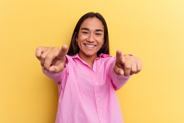 Wall Mural - Young mixed race woman isolated on yellow background cheerful smiles pointing to front.