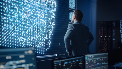 Fototapete - Middle Aged Bearded Senior Project Manager Stands Next to Big Screen with Neural Network. Professional Computer Data Science Engineer Work in a System Control and Monitoring Office.