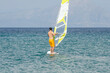 © Nikolaos - Man on Windsurfing Board in the Sea. Summer Water Sport Activities in Greece. Sea and Mountain in Background