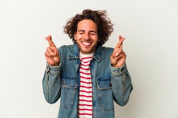 Young caucasian man isolated on white background crossing fingers for having luck