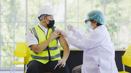 COVID-19 Vaccination station in construction industry. Doctor are vaccinating to group engineer worker protect COVID-19 or flu in hospital. People wear face mask protection from virus. health welfare