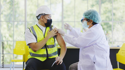 COVID-19 Vaccination station in construction industry. Doctor are vaccinating to group engineer worker protect COVID-19 or flu in hospital. People wear face mask protection from virus. health welfare