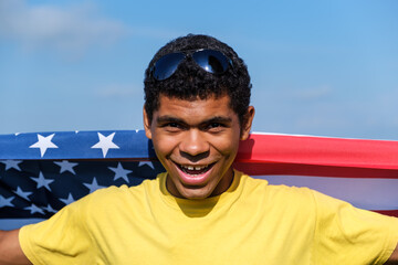 Man looking at camera and proudly holding American flag on his shoulders