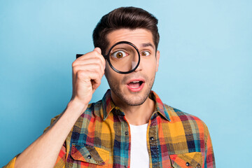 Poster - Portrait of attractive funky guy holding in hand enlarge glass looking find solution isolated over bright blue color background
