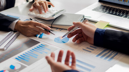 image of business people discussing documents and ideas at a meeting analyzing graphs together.