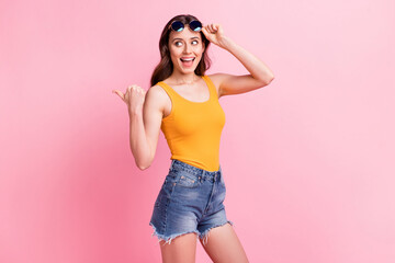 Wall Mural - photo of excited pretty young woman wear yellow singlet dark eyewear pointing thumb up empty space i