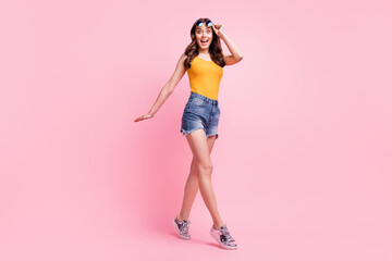 Wall Mural - Photo of charming sweet young woman wear yellow singlet arm dark eyewear walking isolated pink color background