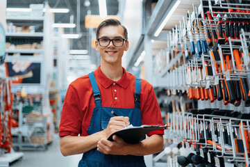 Wall Mural - adviser in a hardware store making notes about the availability of goods on the shelves.