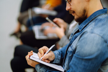 Group of business people meeting in a seminar conference. Audience listening to instructor and making notes. Student training, lecture. Planning, education, analysis, collaborate work in teamwork.