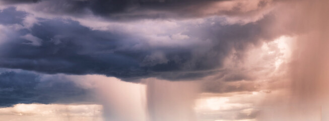 Heavy rainstorm in colorful stormy sky at evening