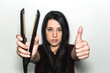 © AliciaFdez - Pretty young woman holding a flat iron in one hand and doing the thumbs up sign with the other. Hair straightener