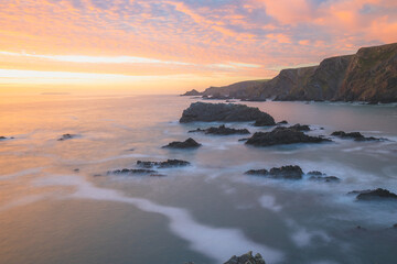 Wall Mural - Dramatic seascape landscape of rock Atlantic coastline with colourful sunset or sunrise sky at Hartland Quay on the North Devon coast in England, UK.