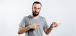 © Daria Lukoiko - Portrait of cheerful young handsome man smiling looking at camera pointing finger to the side on white background with space for advertising mock up