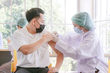 Wall Mural - Portrait of man sitting to getting covid vaccine in clinic or hospital, with hand nurse preparing vaccine to get immunity for protect virus. teenager wearing protective mask.