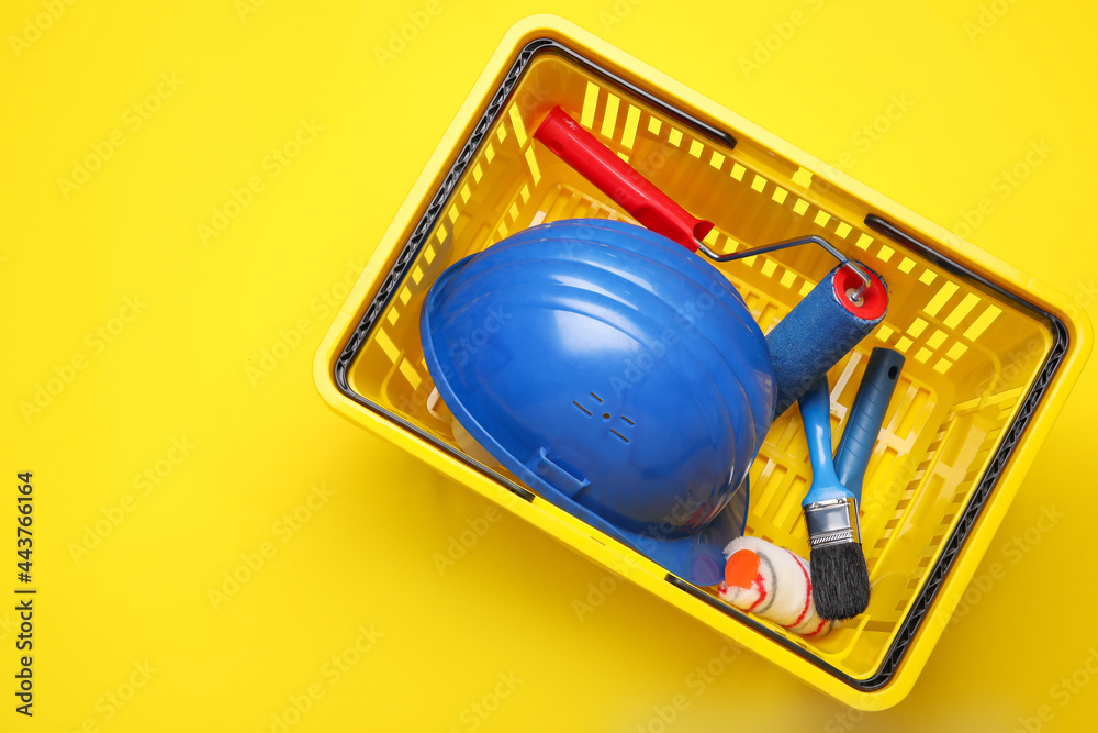 Shopping basket with painter's supplies on color background