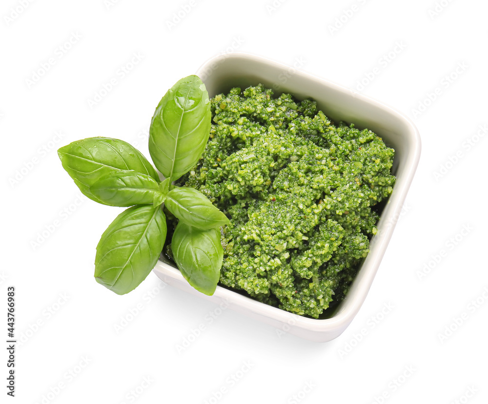 Bowl with fresh pesto sauce and basil leaves on white background