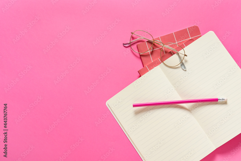 Stylish eyeglasses with notebooks and pencil on color background