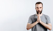 © Daria Lukoiko - A man with crossed palms. The guy reads a prayer with his palms crossed in front of him. Portrait of handsome young man n white background with space for advertising mock up