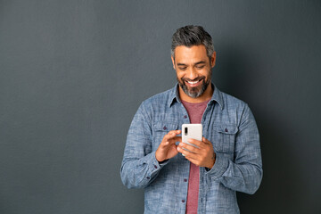 mature indian man messaging on smartphone