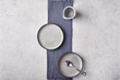 © Vitalii - Empty light plates with saucer, spoon and napkin set on gray graphite textured background. Top view, copy space