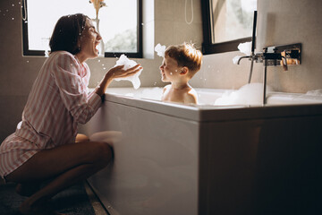 Mother washing little son in bathroom