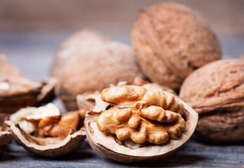 Wall Mural - heap of walnuts with nutshell on wooden background