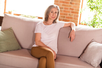 Poster - Photo of charming sweet old woman dressed white t-shirt sitting sofa smiling indoors flat home house