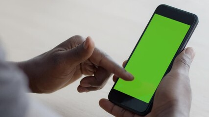 Aufkleber - Close up shot of black guy scrolling touchscreen of modern smartphone, gadget with green chroma key screen