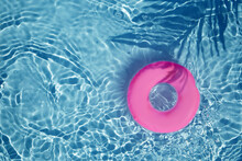 Pink Pool Float Ring Floating In A Refreshing Blue Swimming Pool. Top View