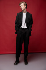 Young guy in a casual suit and white T-shirt on a red background looks to the side