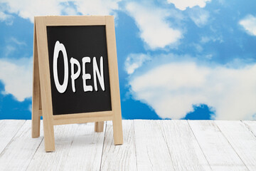 Wall Mural - Open sign on standing chalkboard with sky