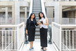 © Bhaven - Two smiling  Indian women looking into a phone as they come down an escalator in an urban corporate setting,