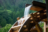 The mill wheel rotates under a stream of water, close up.