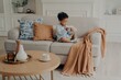 © VK Studio - Small lovely Afro American child sitting on sofa and playing alone in living room