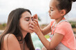 Cute little girl using children make up with big sister outdoor at city park - Family love concept