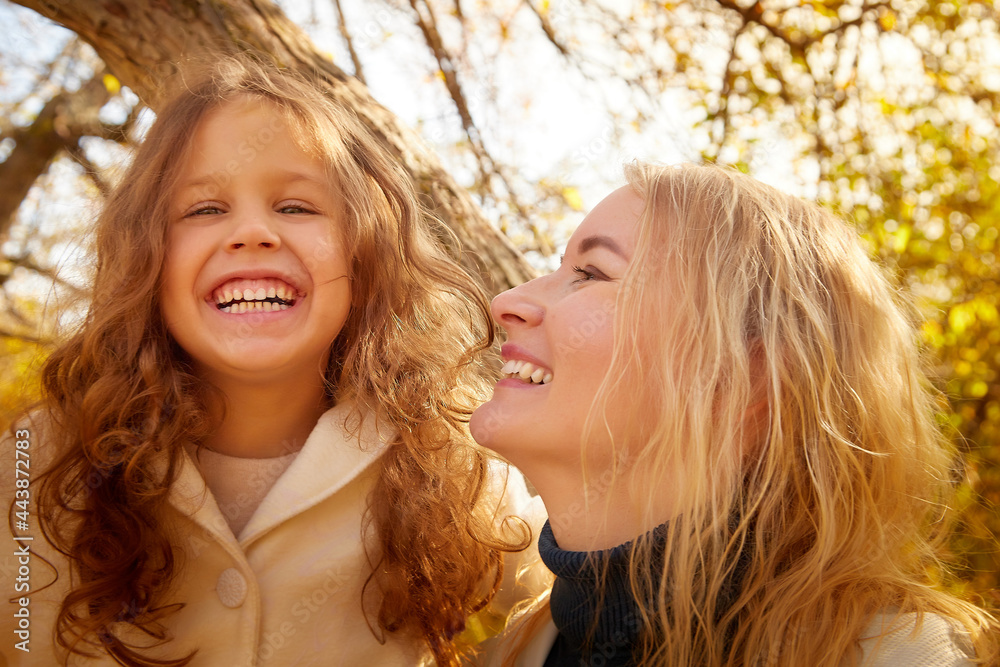 Mother and young little girl with blonde hair in an autumn park on a ...