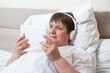 © Zuev Ali - An elderly music lover is resting on the bed. Grandma is listening to music.