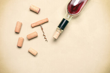 Wall Mural - Flat lay incomplete bottle of red wine with cork and corkscrew on beige concrete background. Top view.