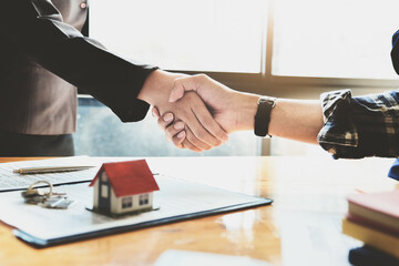 Focus on the congratulatory handshake. The real estate agent agrees to buy the home the customer at the agent's office. concept agreement.