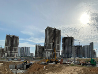 Wall Mural - Tall modern beautiful buildings and houses are concrete skyscrapers built industrially using monolithic frame technology with the help of construction equipment and cranes